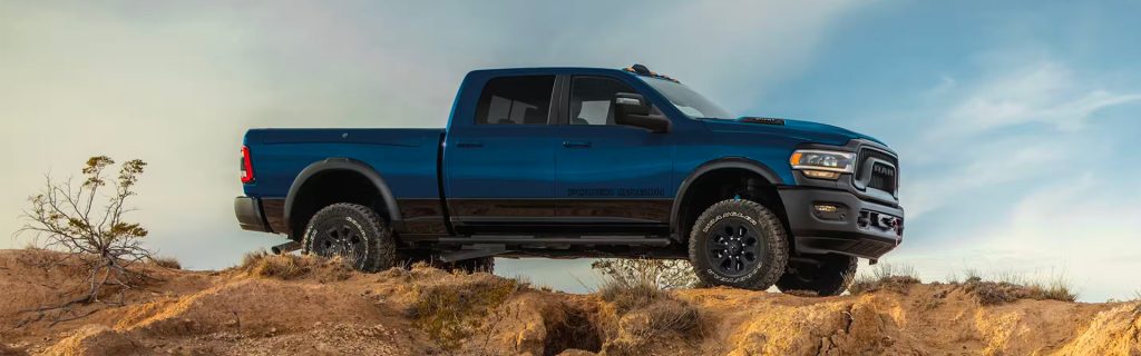 Blue RAM Power Wagon pickup truck on a rocky off-road terrain.