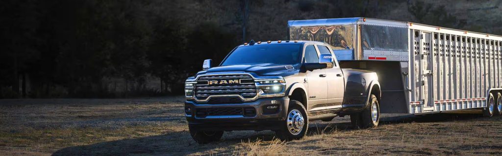 2026 RAM 3500 truck towing a trailer in rugged terrain