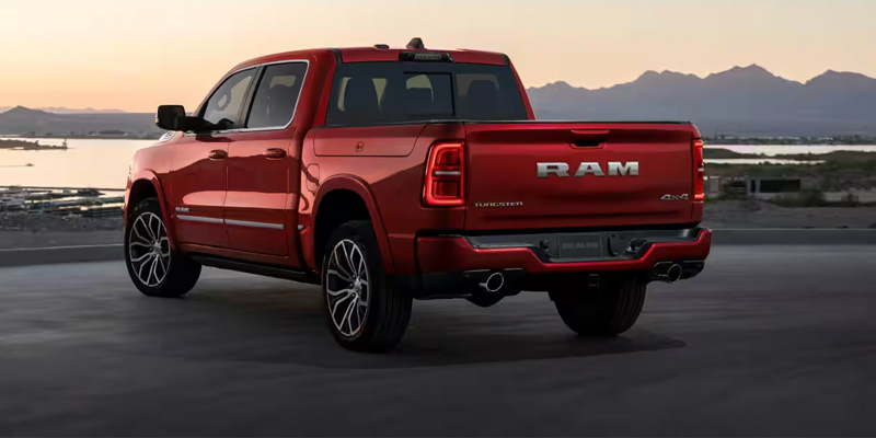 Red Ram pickup truck parked near a scenic mountain landscape at sunset