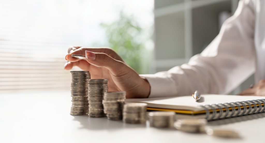 Hand placing coins into stacks for financial planning and savings